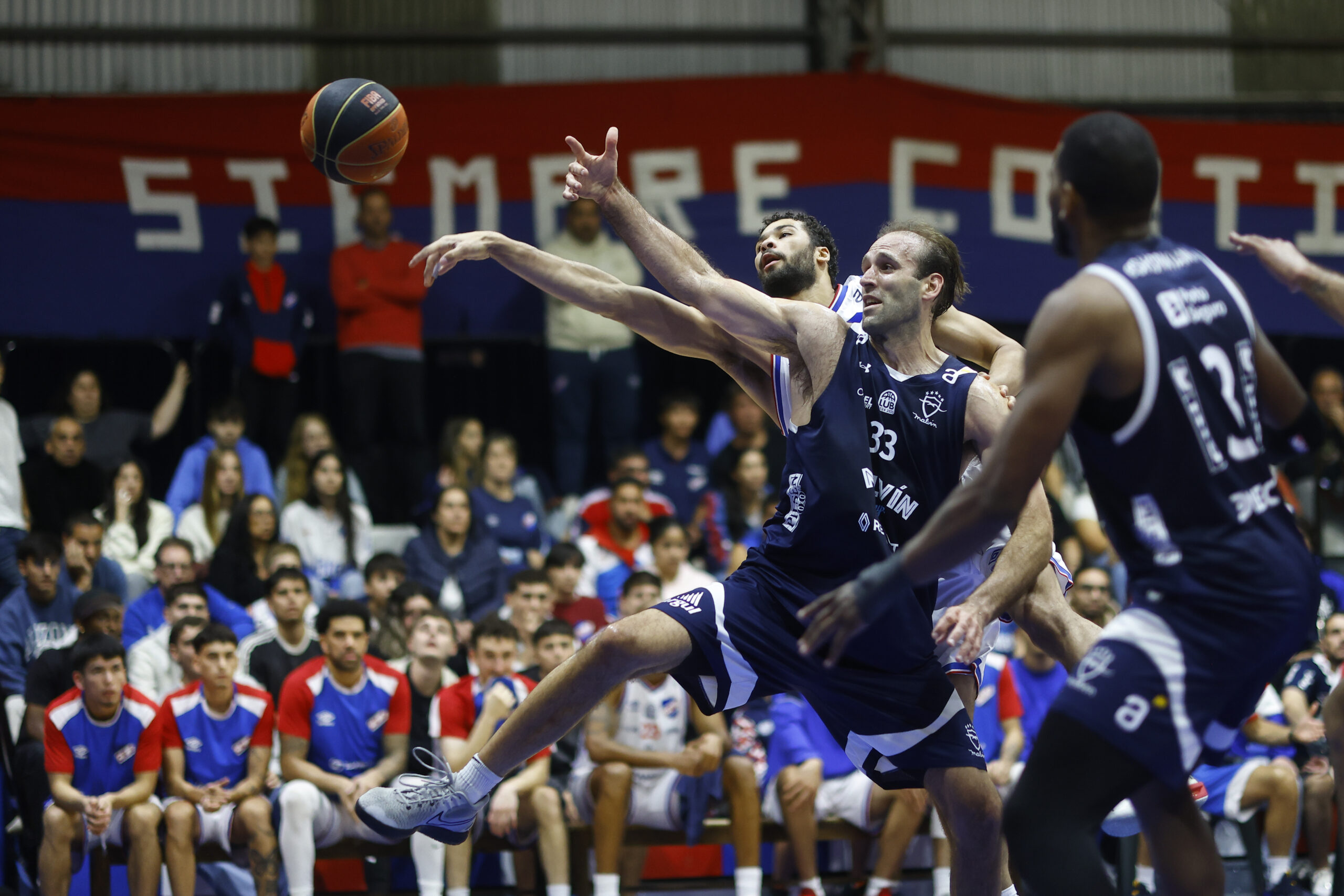 Ernesto Ryan-20250331ER-0019./ Kiril Wachsmann, de Malvín, Joao Pereira, de Nacional, durante el partido Nacional vs Malvín por la quinta fecha de la Fase Campeonato de la Liga Uruguaya de Básquetbol, el 31 de marzo de 2025 en el Polideportivo del Gran Parque Central, en Montevideo. / Foto: Ernesto Ryan, Agencia Gamba.-